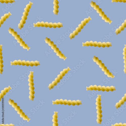 Fusilli pasta random flat lay on blue background without shadow. can be used as raw pasta background, poster, banner not pattern.