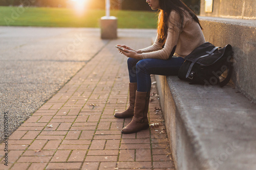 Young mixed race woman - asian & caucasian - using smart phone outside on steps photo