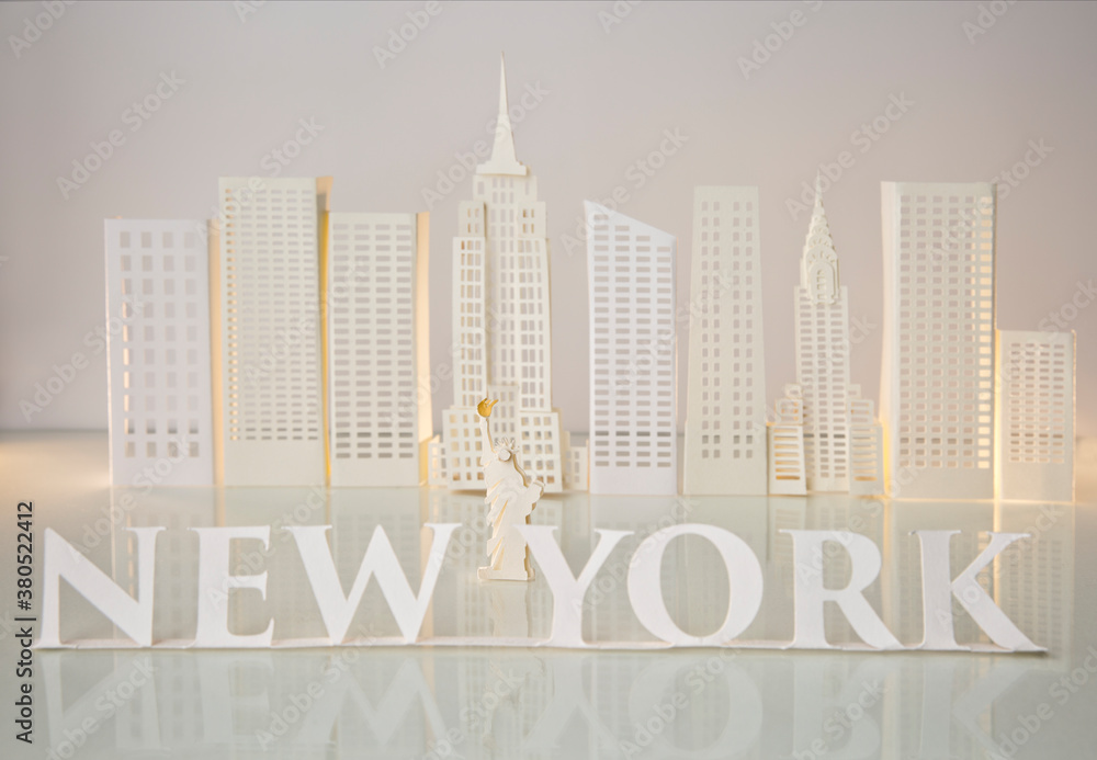 New York written with serif letters with Statue of Liberty in the middle and skyscrapers Stock