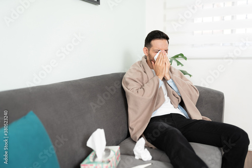 Young man with a cold sneezing