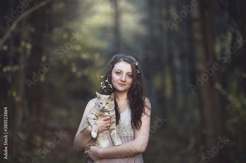 A young woman poses with her cat in the woods at sunset photo