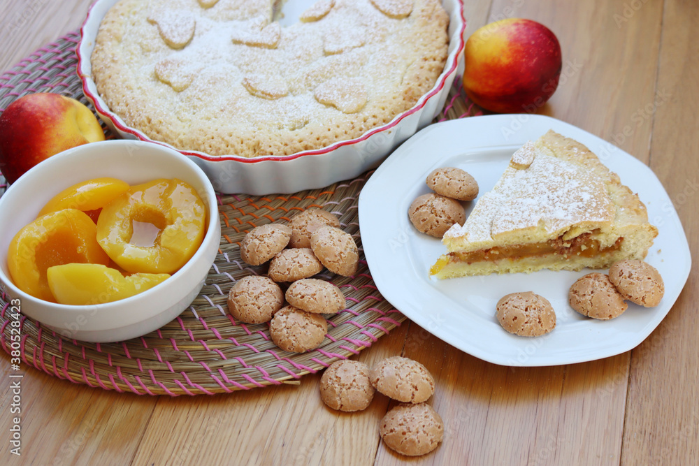 Sweet cake with canned peaches on syrup and italian Amaretti cookies on wooden table Sweet cake with canned peaches on syrup and italian Amaretti cookies on wooden table