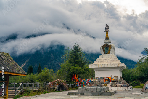 A white pagoda in a valley of mountains in Sichuan, China.