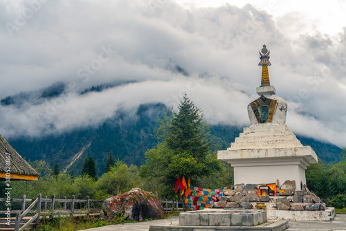 A white pagoda in a valley of mountains in Sichuan, China.