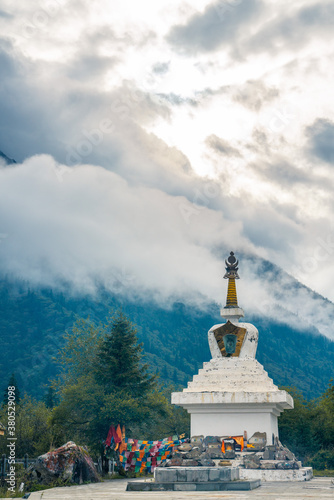 A white pagoda in a valley of mountains in Sichuan, China.