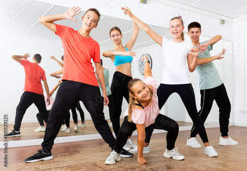 Group portrait of jolly teenagers with young female choreographer in modern dance studio