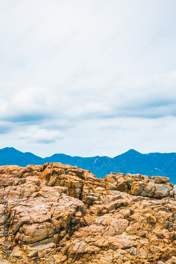 Beautiful natural composition, vivid orange brown yellow stone rock shabby cliff cracks, cumulus cloud sky, mountain background. Vacation after pandemic, beauty nature power. Vertical stories format