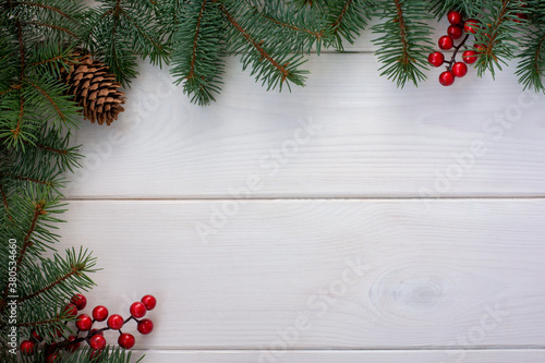 Christmas tree branches with pinecone and red berries on white wooden background and copy space for your text. Flat lay