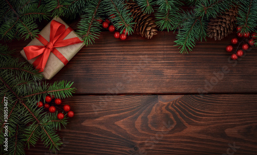 Christmas tree, gift, pinecones, red berries on a wooden brown background.Copy space for your text. Flat lay