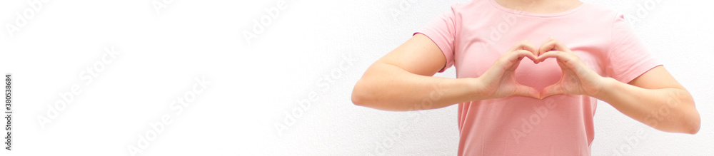 Female in pink shirt showing heart with two hands on white backgrounds. Concept of love, health, gratitude, peace. Banner. Female in pink shirt showing heart with two hands on white backgrounds. Concept of love, health, gratitude, peace. Banner.