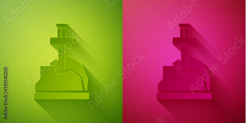 Paper cut Sword in the stone icon isolated on green and pink background. Excalibur the sword in the stone from the Arthurian legends. Paper art style. Vector.