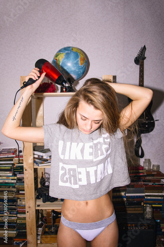 Young blonde woman blow drying hair photo