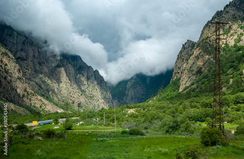 The road enters the gorge  steep cliffs on both sides  thunderclouds overhang  touch the peaks. Caucasus mountains  Russia