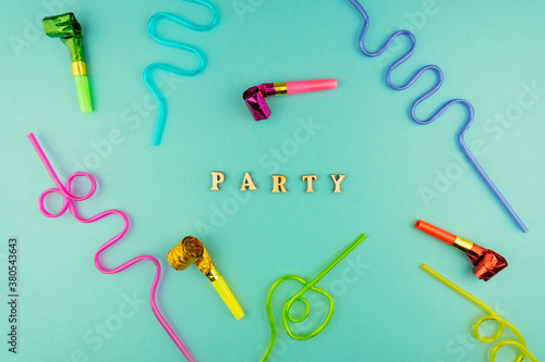 Bright festive party background - cocktail straws and party whistles on blue background.