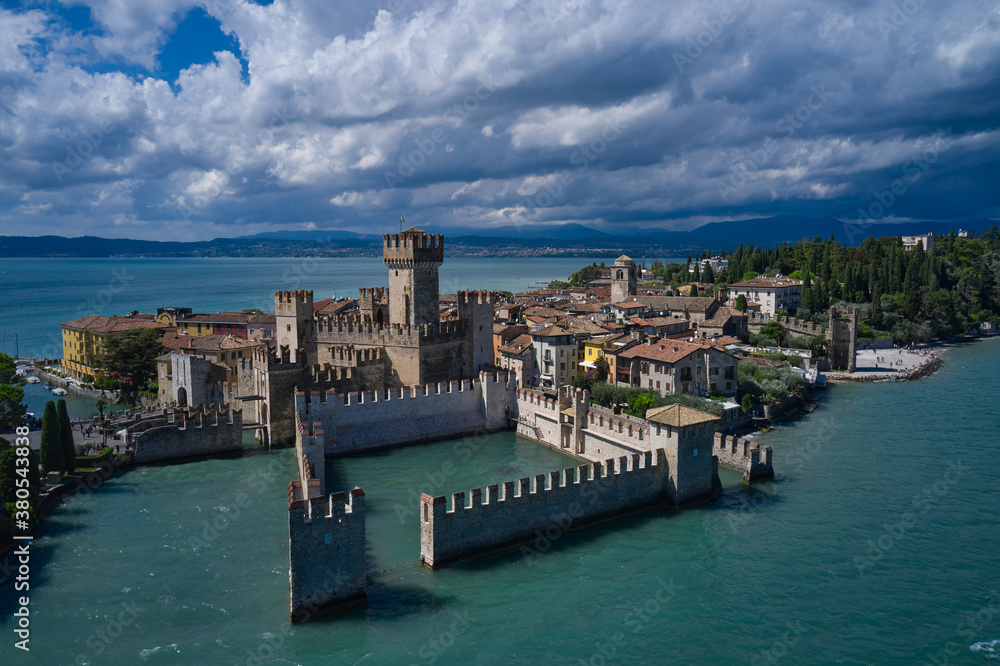 Aerial view on Sirmione sul Garda. Italy, Lombardy. Rocca Scaligera Castle in Sirmione. Cumulus clouds over the island of Sirmione. Aerial photography with drone.