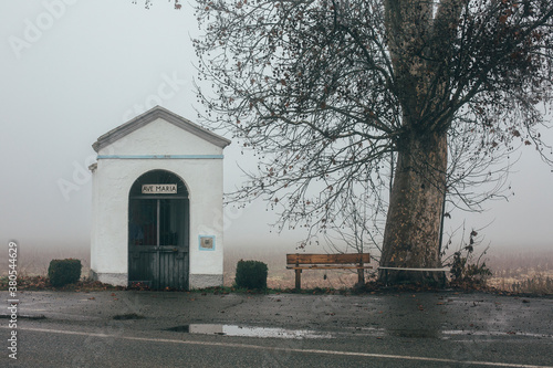 Wooden becnh close to tiny chapel with Ave Maria write photo