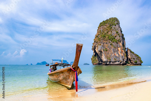 Traditional Tourist Sightseeing Long Tail Boat on Ao Phra Nang Beach with Great Limestone Rock Background in Turquoise Andaman Sea in Summer, Krabi, Thailand photo