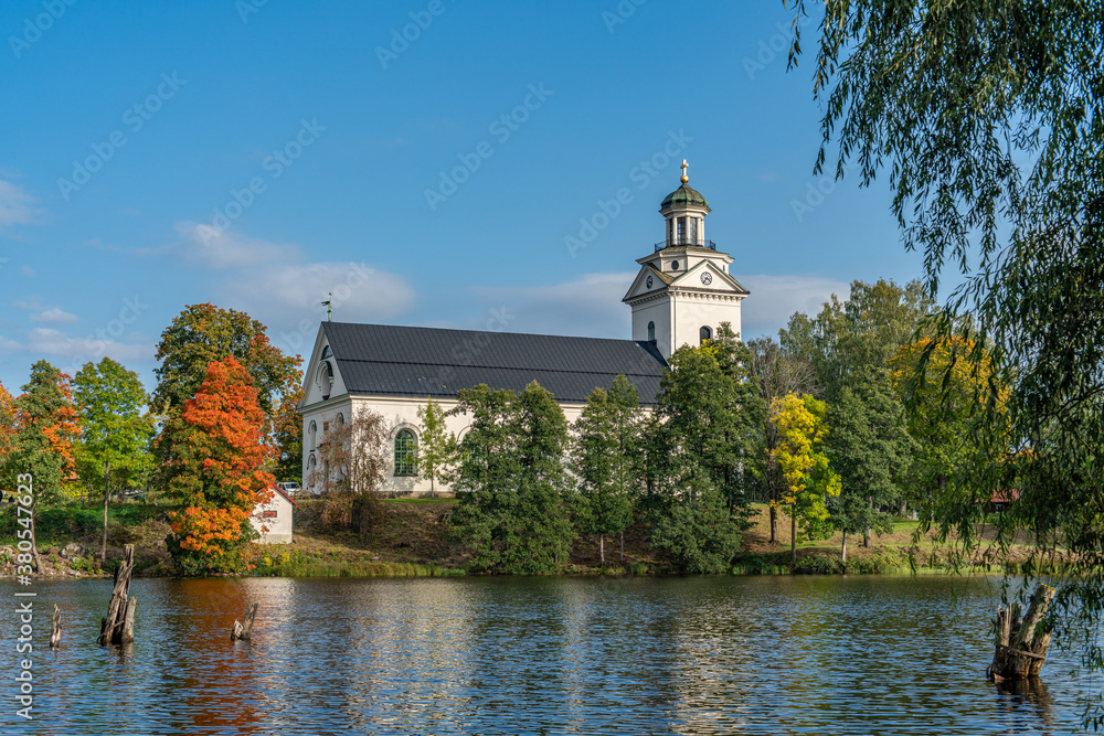 White church with autumn colored trees in sunlight