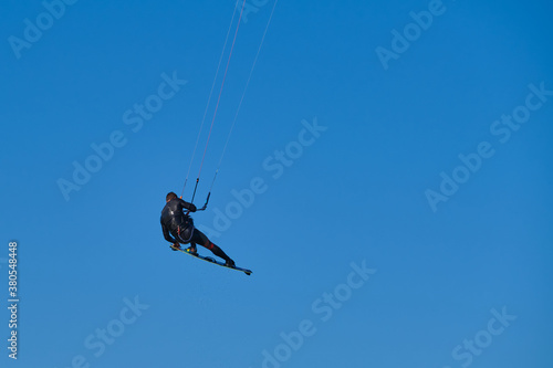 Kitesurfer in wetsuit in the jump on a background of blue sky