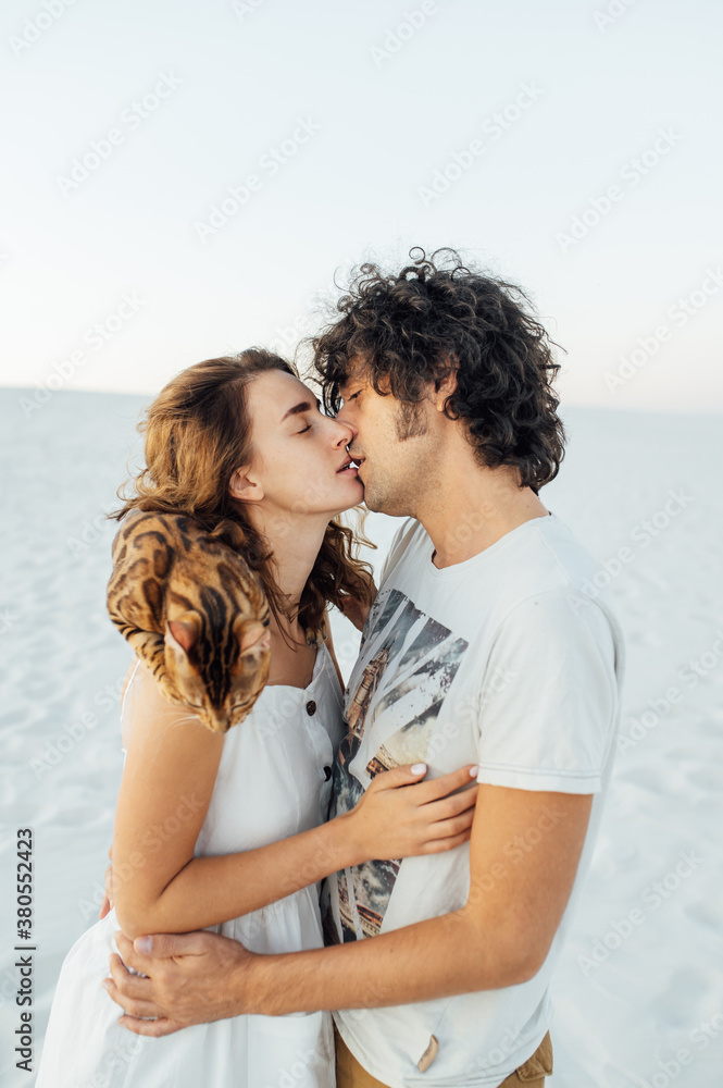 Beautiful couple of lovers hug each other and hold the cat in their arms Beautiful couple of lovers hug each other and hold the cat in their arms