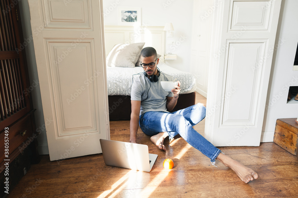 Latin man sitting on floor working with laptop.
