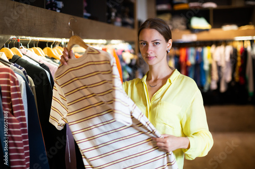 Pretty woman chooses fashionable t-shirt in store. High quality photo