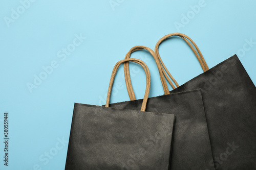 Black paper bags on blue background, space for text