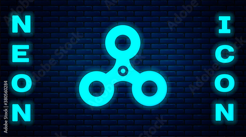 Glowing neon Fidget spinner icon isolated on brick wall background. Stress relieving toy. Trendy hand spinner. Vector.