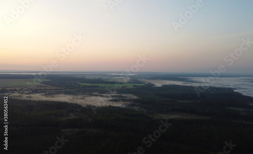 Top view at sunrise on a calm lake and forest © Payllik