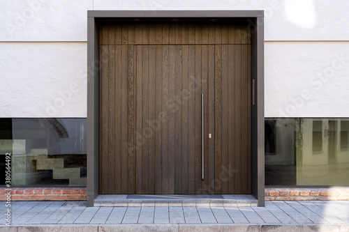 Massive wooden entrance door to modern white house with paving footpath in the city. New, modern architecture, exterior design © boumenjapet
