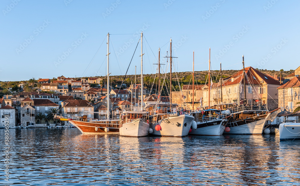 View of the promenade of Milna, Croatia, with yachts, ships and houses at sunset