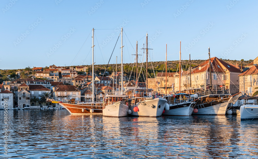 Fototapeta premium View of the promenade of Milna, Croatia, with yachts, ships and houses at sunset