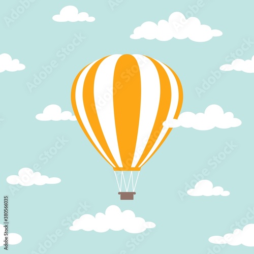 Orange hot air balloon flying in the powder blue sky with clouds.