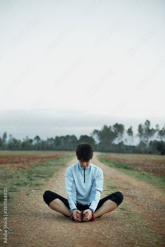 Woman sitting and stretching muscles outdoors Woman sitting and stretching muscles outdoors