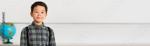 Foto Panoramic shot of asian schoolboy looking at camera in classroom