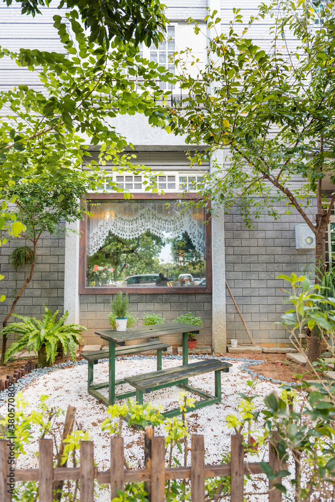 Designed backyard with trees, plants, wooden table and chairs Designed backyard with trees, plants, wooden table and chairs