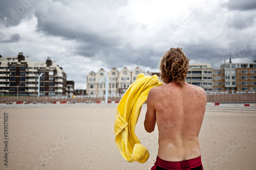 Young man comes back from swimming and walks back photo