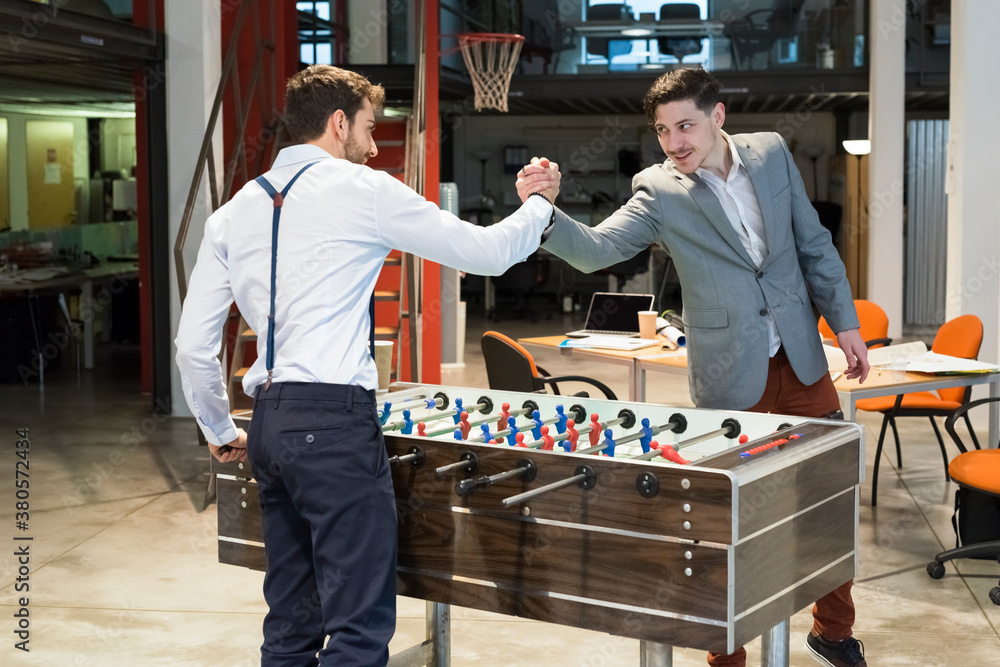 Businessmen playing table-football in a cool office Businessmen playing table-football in a cool office