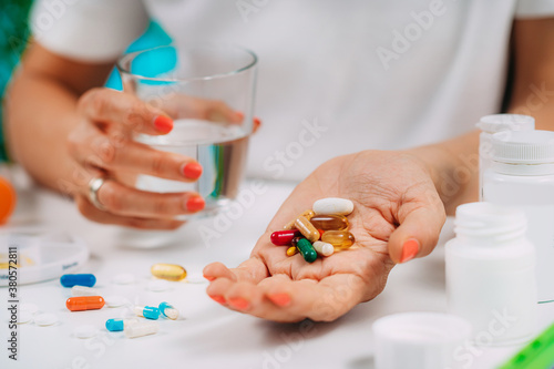 Supplementation. Woman holding a myriad of vitamin and mineral supplements in her hand.