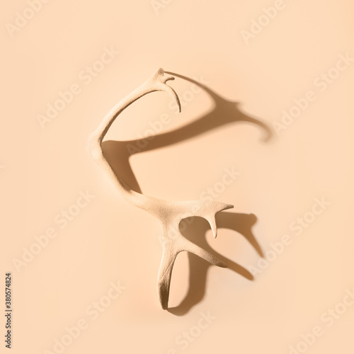 Painted deer antlers with shadow on beige background. Square image. Christmas concept.