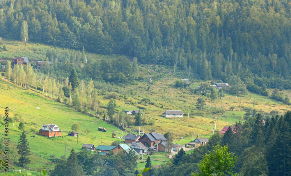 Mountain forest green landscape with houses and a far village.