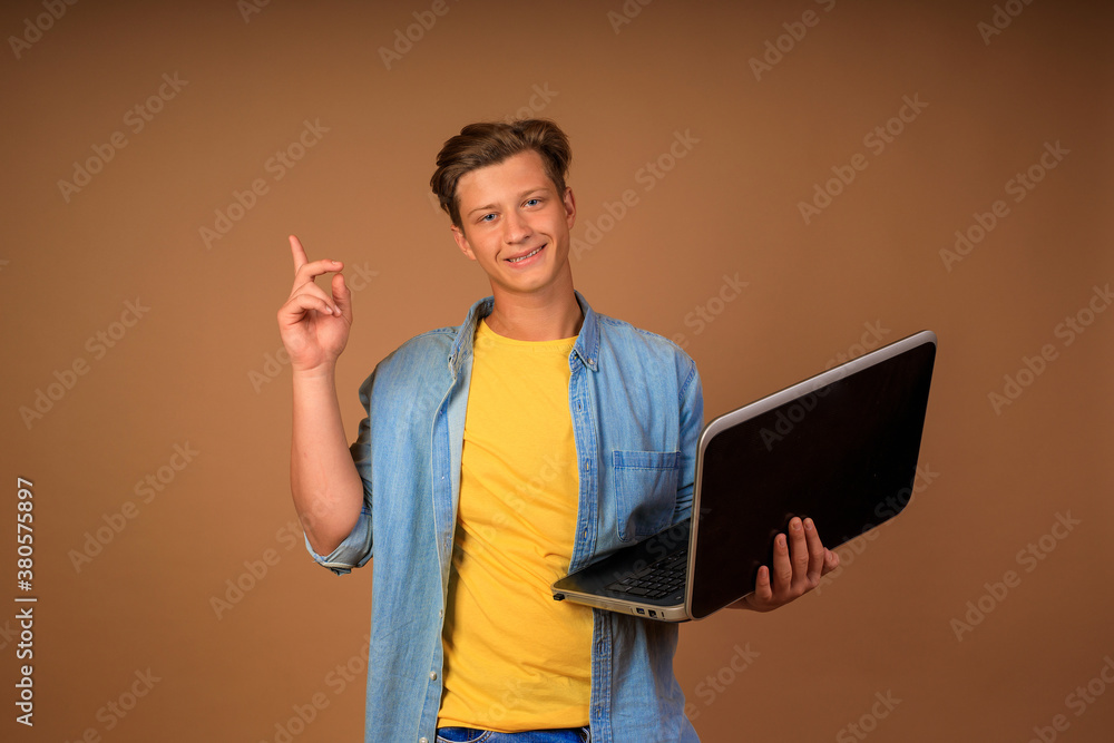 modern remote work. portrait of a young guy with a laptop in his hands on a beige background modern remote work. portrait of a young guy with a laptop in his hands on a beige background