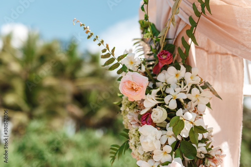 Fototapeta Naklejka Na Ścianę i Meble -  Wedding ceremony. Arch, decorated with pink and white flowers, tropical greenery, close up