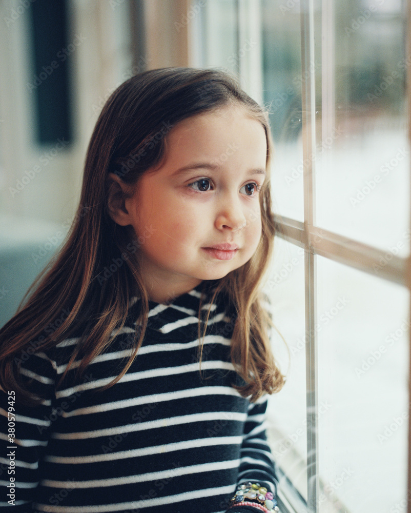 Beautiful young girl looking out a window Beautiful young girl looking out a window