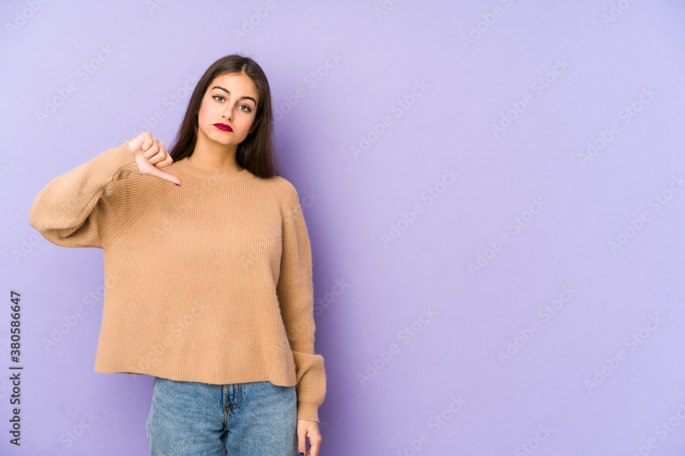 Young caucasian woman isolated on purple background showing a dislike gesture, thumbs down. Disagreement concept. Young caucasian woman isolated on purple background showing a dislike gesture, thumbs down. Disagreement concept.