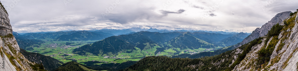 Panorama von Saalfelden am Steinernen Meer und Leogang bis zum Großklockner eingerahmt von den Felsen der Kasawand bei bewölktem Himmel