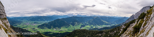 Panorama von Saalfelden am Steinernen Meer und Leogang bis zum Großklockner eingerahmt von den Felsen der Kasawand bei bewölktem Himmel