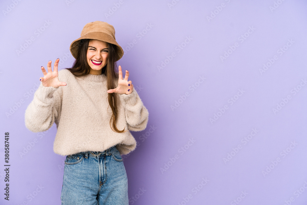 Young caucasian woman isolated on purple background showing claws imitating a cat, aggressive gesture.