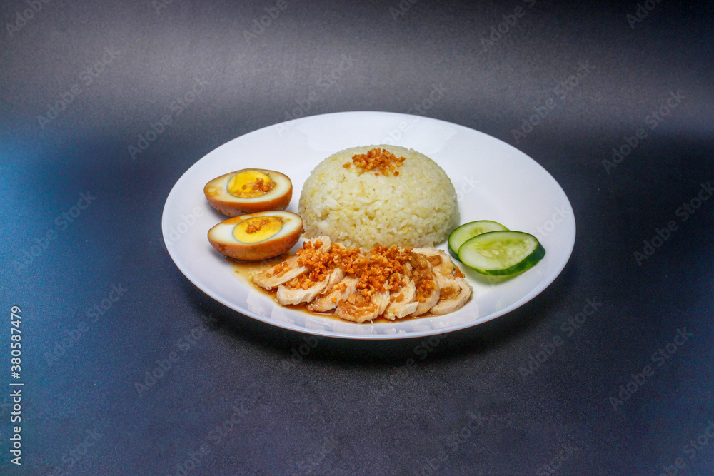Hainanese chicken rice or steamed chicken rice with sweet soy sauce egg plus cucumber slices. Served on a white plate.
Hainanese chicken rice or steamed chicken rice with sweet soy sauce egg plus cucumber slices. Served on a white plate.