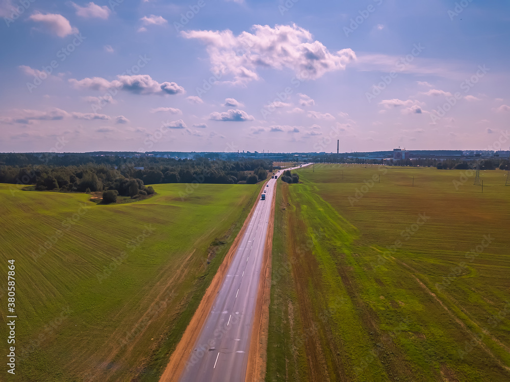 Drone view of the road in the middle of a field on a Sunny day